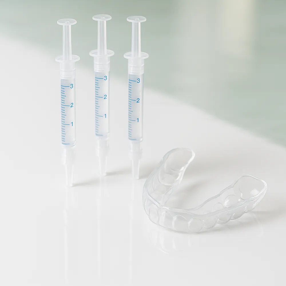 Professional teeth whitening tray and syringes on a glossy white surface